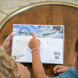 Two children examining the back cover of the Tooth Fairy Collection Gifts book, showing the interactive and engaging elements included.